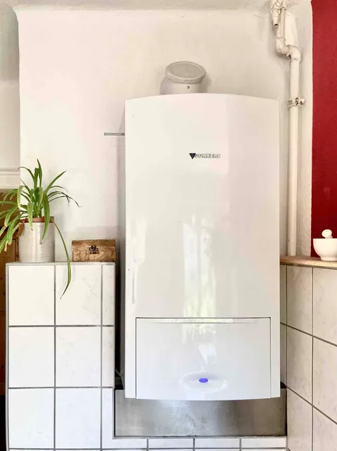 Junkers-combiketel aan de muur van een woonkeuken, met rookgasafvoer